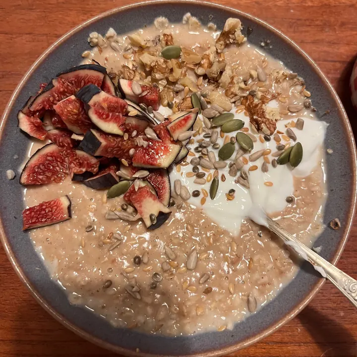 Oats topped with figs, seeds and yoghurt in a grey bowl