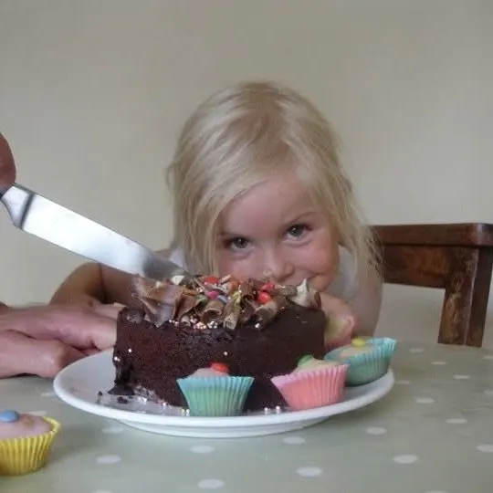 Baby Martha peeking over a chocolate birthday cake